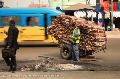 A cart carrying woodfuel in the middle of a busy city 